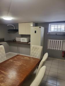 a kitchen with a wooden table and white chairs at Rooms4Rest Wiertnicza - Private rooms for tourists - ATR Consulting Sp, z o,o, in Warsaw