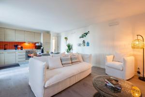 a living room with a white couch and a kitchen at MAISON SUR MER - Garage & Jardin Privè in Roquebrune-Cap-Martin