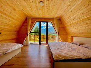 two beds in a wooden room with a large window at Villa Dardania in Peje