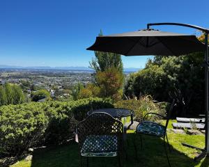 una mesa y sillas bajo una sombrilla en una colina en Cashmere Hills Mountain Views Apartment, 