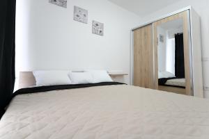 - une chambre avec un grand lit blanc et un miroir dans l'établissement Porta Apartment, à Skopje