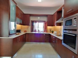 cocina grande con armarios de madera y microondas en Casa Bolota, en Cuba