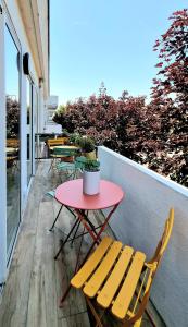 une table et des chaises rouges sur un balcon avec une table et des chaises dans l'établissement L'Étoile Des Sables - Maison de ville climatisée classée 4 étoiles - 4 personnes - Plage de la Grande Conche à 200m - ROYAN, à Royan