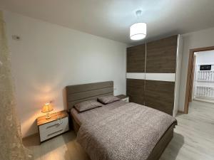 een slaapkamer met een bed en een nachtkastje met een lamp bij Grace's Centre Apartment in Shkodër