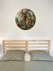 uma pintura de palmeiras numa parede acima de uma cama em “Sweet boho penthouse” in city center em Lahr