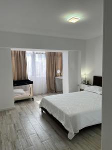 a white bedroom with a bed and a window at Luxurious apartment with 3 rooms and 2 bathrooms in Corabia in Corabia