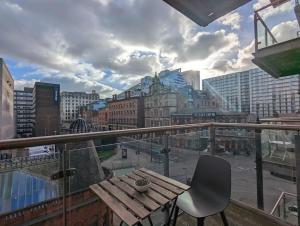 uma mesa e cadeira de madeira numa varanda com uma cidade em 2 Bed 2 Bath Flat Central Manchester em Manchester