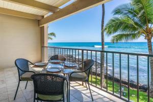 Una mesa y sillas en un balcón con vista al mar. en New Top Hawaii Oceanfront 2BR/2BR with White Sand Beach-Kona Bali Kai 206, en Kailua-Kona