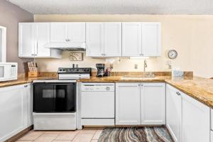 a kitchen with white cabinets and a black appliance at New Top Hawaii Oceanfront 2BR/2BR with White Sand Beach-Kona Bali Kai 206 in Kailua-Kona
