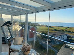 Habitación con ventana grande con silla y vistas al océano. en DÚPLEX DE LUJO EN FOZ CON VISTAS al MAR, en Foz
