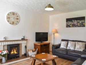 a living room with a couch and a fireplace at Glen Nevis Cottage in Port Elphinstone