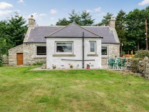 a stone house with a yard in front of it at Glen Nevis Cottage in Port Elphinstone