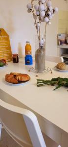 einen Tisch mit einer Vase Blumen und einem Teller Brot in der Unterkunft La Caravelle 2 entre Plage et Centre Ville in Le Grau-du-Roi