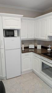 een keuken met witte kasten en een witte koelkast bij Apartamento a estrenar a 300 m de la playa de San Lorenzo en Gijón in Gijón