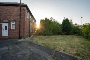a brick house with the sun setting in a yard at Comfy 3Bed House-Parking-Garden in Newcastle upon Tyne
