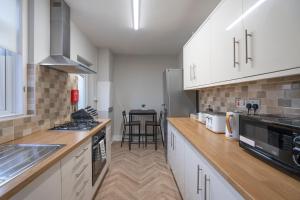 cocina con armarios blancos y fogones en Comfy 3Bed House-Parking-Garden en Newcastle