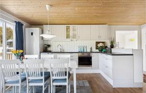 uma cozinha com armários brancos e uma mesa e cadeiras em Cozy Home In Sveio With Wifi em Sveio