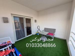 een kamer met een groene vloer en een tafel. bij قريه امواج الساحل الشمالى in Abû Zeira