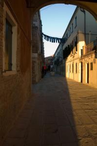 an empty alley with an archway in a building at Veneziacentopercento Rooms in Venice