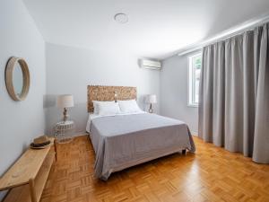 ein weißes Schlafzimmer mit einem Bett und Holzboden in der Unterkunft Villa Kostamaria in Petrití