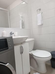 a white bathroom with a toilet and a sink at Departamentos Egaña in Puerto Montt