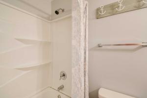 a white bathroom with a shower and a toilet at Walk to Atlantic Beach Family Gem with Fenced Yard in Myrtle Beach +21 photos