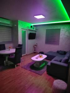 uma sala de estar com um sofá, uma mesa e luzes verdes em Grand apartman em Belgrado