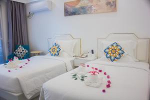 two beds in a hotel room with flowers on them at Bohol Dolphin Bay Resort in Panglao
