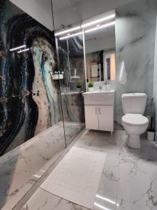 a bathroom with a toilet and a painting on the wall at Elite Studio Militari Residence in Chiajna