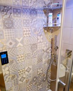 y baño con ducha y pared de azulejos. en La Casetta Nelle Mura en Terracina