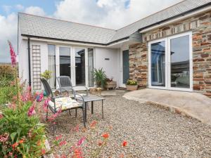 a brick house with a patio with chairs and flowers at Bonnie Cottage in Tintagel