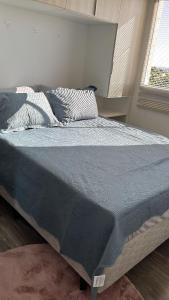 Bett in einem Schlafzimmer mit blauer Bettdecke und Kissen in der Unterkunft Apartamento novo linha verde - up life in Curitiba