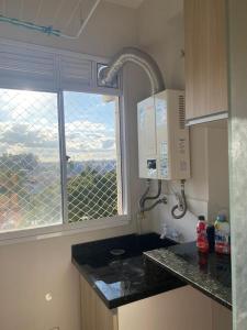 eine Küche mit einem Waschbecken und ein Fenster mit Aussicht in der Unterkunft Apartamento novo linha verde - up life in Curitiba