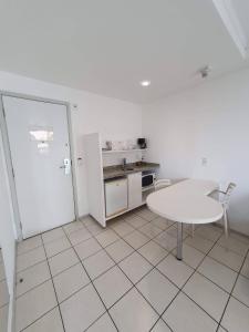 eine Küche mit einem weißen Tisch, einem Tisch und Stühlen in der Unterkunft Praia do canto apart 3 in Vitória