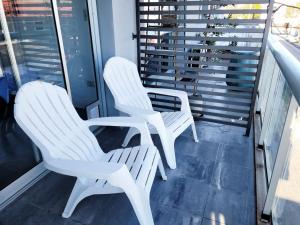 2 sillas blancas en la parte superior de un balcón en Departamento céntrico villa ramallo en Ramallo