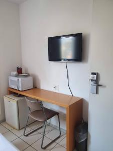 einen Schreibtisch mit einem TV auf einer Wand in der Unterkunft Praia do canto 502B in Vitória