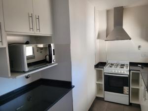a white kitchen with a stove and a microwave at Departamento céntrico Villa Ramallo in Ramallo