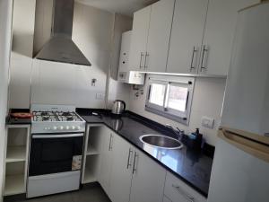 a kitchen with white cabinets and a sink and a stove at Departamento céntrico villa ramallo in Ramallo