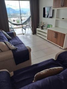a living room with a couch and a large window at MAR & SERRA - PRAIA do MORRO in Guarapari