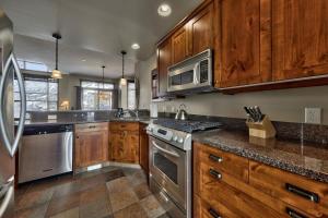 a kitchen with wooden cabinets and stainless steel appliances at Trappers Landing #27 By Bear Country in Sun Peaks