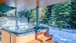 a jacuzzi tub on a deck with trees at Snow Creek Village #37 By Bear Country in Sun Peaks