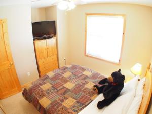 a teddy bear sitting on a bed in a bedroom at Crystal Forest #11 By Bear Country in Sun Peaks