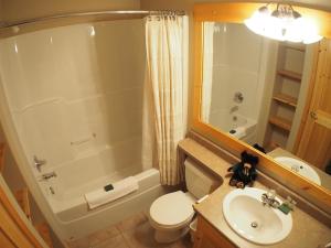 a bathroom with a toilet and a tub and a sink at Crystal Forest #11 By Bear Country in Sun Peaks