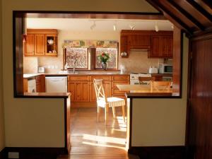 - une cuisine avec des placards en bois, une table et des chaises dans l'établissement Cairngarth Cottage, à How