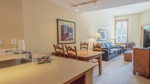 cocina y sala de estar con mesa y sofá en Fireside Lodge #419 By Bear Country, en Sun Peaks