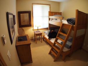 a bedroom with bunk beds with a person laying on the bed at Crystal Forest #53 By Bear Country in Sun Peaks
