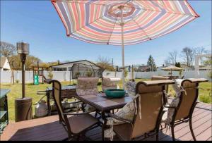 een tafel en stoelen met een parasol op een terras bij luxurious home spacious yard & above ground pool in Shirley