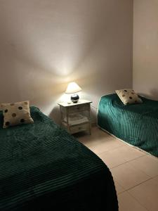 Habitación con 2 camas y mesa con lámpara. en Aromas de Azahar en Bella Vista