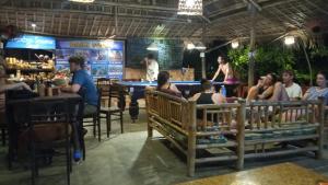 a group of people sitting at tables in a restaurant at The Seaside Bungalow Hostel and Bar in Hoi An