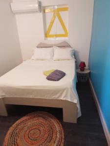 a small bedroom with a white bed with a rug at Les Remparts de vieux fort 2 in Saint-Louis